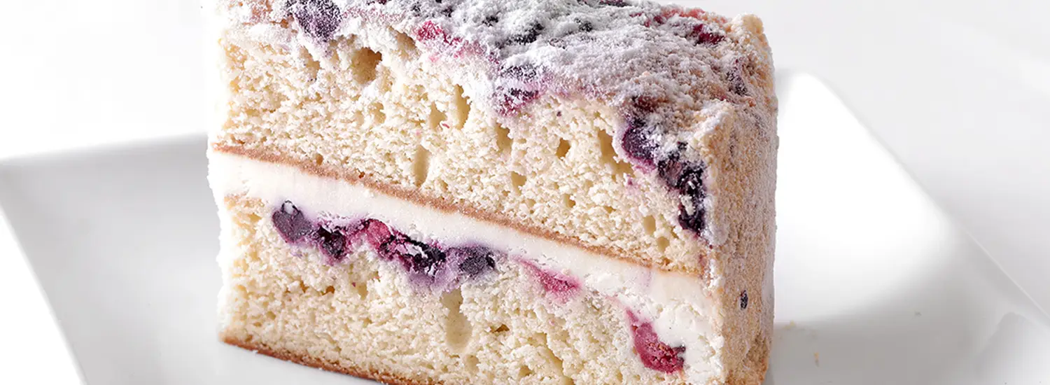 Sysco Exclusive Lemon Berry Mascarpone Cake at Ginsberg’s Foods features layers of lemon cream, topped with blueberries, cranberries, and vanilla crumb for a bright, refreshing dessert.